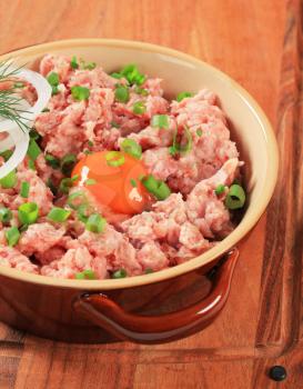 Raw minced meat and egg yolk in a ceramic pot