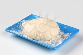Raw pizza dough on a blue plate
