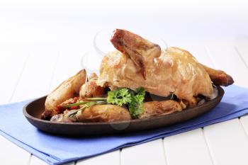 Cooked chicken served with baked potatoes and vegetables