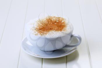 Cup of cappuccino with rich milk froth and nutmeg on top