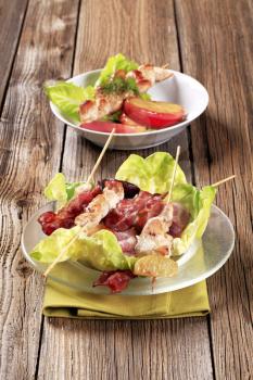 Grilled chicken skewers and bacon served on lettuce leaves