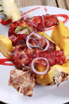 Meat skewers and crispy bacon strips served on pineapple peel