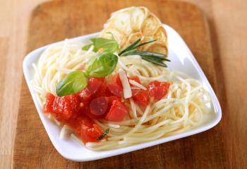 Spaghetti, peeled tomato and baked garlic - closeup