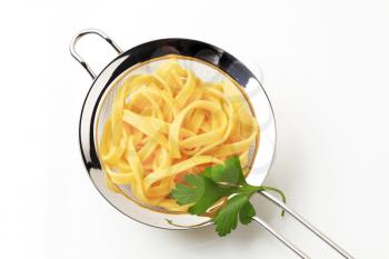 Cooked ribbon pasta in a metal sieve