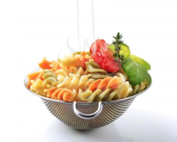 Tricolor corkscrew pasta in a metal sieve