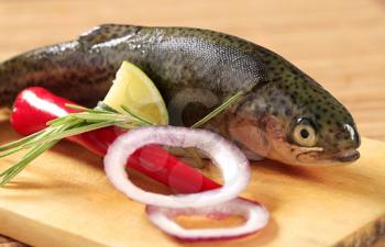 Fresh trout and other ingredients on cutting board