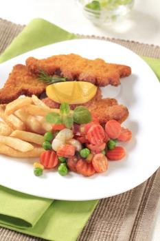Fried fish served with French fries and mixed vegetables