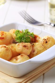 Cheese coated potatoes in square ceramic dish