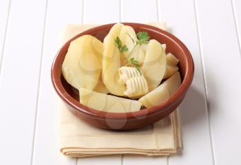 Dish of boiled potatoes and curl of butter 
