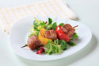Grilled pork skewer with fresh salad greens 