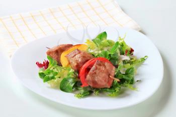 Grilled pork skewer with fresh salad greens 