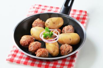 Pan-fried meatballs and potatoes in a fry pan