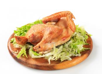 Crispy skin roast chicken with shredded lettuce on cutting board