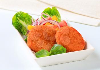 Fried cheese or fish cakes with fresh vegetable salad 