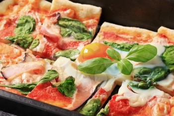 Pizza with prosciutto, spinach leaves and sunny side up egg on top