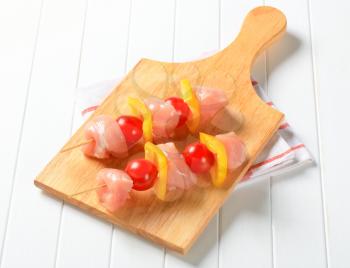 Pieces of raw chicken and vegetables on skewers