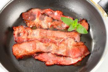Strips of fried bacon on frying pan