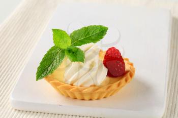 Custard tart topped with cream and raspberry