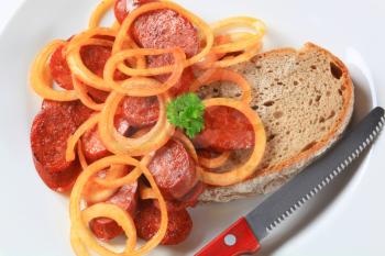 Pan fried slices of spicy sausage with onion