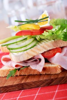 Ham sandwich topped with fresh vegetables - closeup