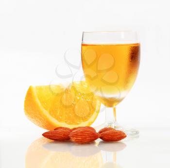 Glass of cold drink, wedge of orange and almonds