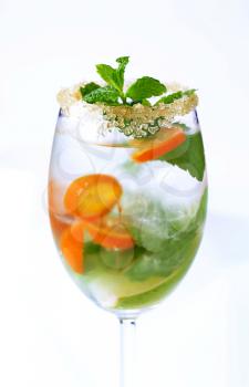 Glass of iced drink with lime, kumquat and mint