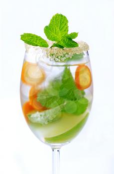 Glass of iced drink with lime, kumquat and mint
