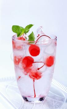 Glass of iced drink with maraschino cherries