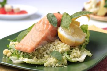 Salmon fillet with couscous and rocket salad garnished with fresh sage leaves
