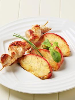 Chicken skewer and slices of baked apple 