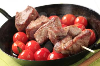 Pork kebab and cherry tomatoes in a pan
