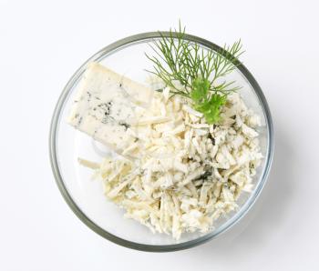 Blue cheese grated in a bowl garnished with dill