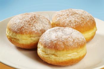 Three fresh doughnuts
 sprinkled with icing sugar
