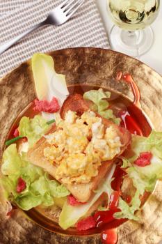 Toast and scrambled eggs on nest of fresh salad