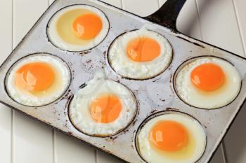 Six fried eggs in an old pan