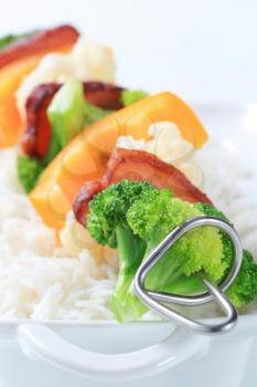 Vegetable skewer with slices of bacon and white rice