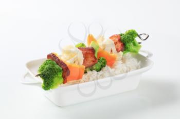 Vegetable skewer with slices of bacon and white rice