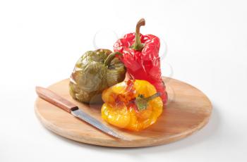 Three roasted bell peppers on a cutting board