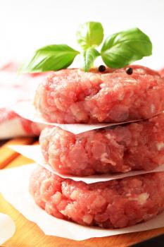 Pile of raw meat patties on a cutting board