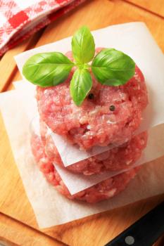 Pile of raw meat patties on a cutting board