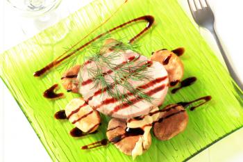 Pork loin steak and baked potatoes poured with balsamic reduction