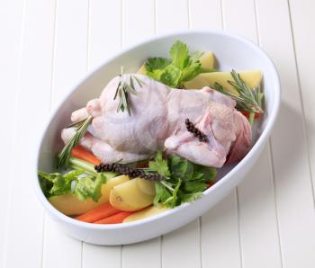 Raw chicken and vegetables in a casserole dish