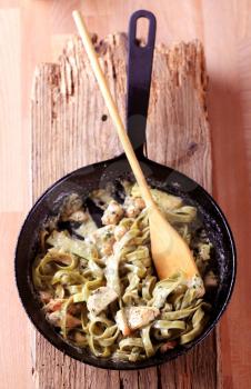 Preparing pasta dish - Spinach fettuccine with chicken meat, basil pesto and cream
