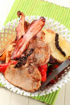 Juicy pork chops and bacon with  potato and red peppers
