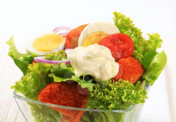 Fresh salad with fried breaded cheese and sliced boiled egg