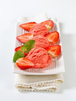 Scoops of strawberry ice cream on a long plate