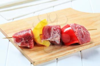 Chunks of raw red meat on wooden skewer