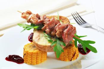 Grilled pork kebab with baked potato and sweet corn