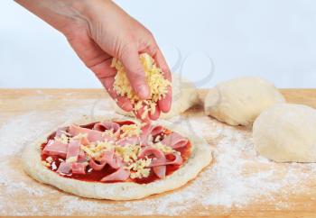 Cook sprinkling shredded cheese over pizza