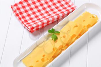 Thin slices of Swiss cheese in a long serving dish